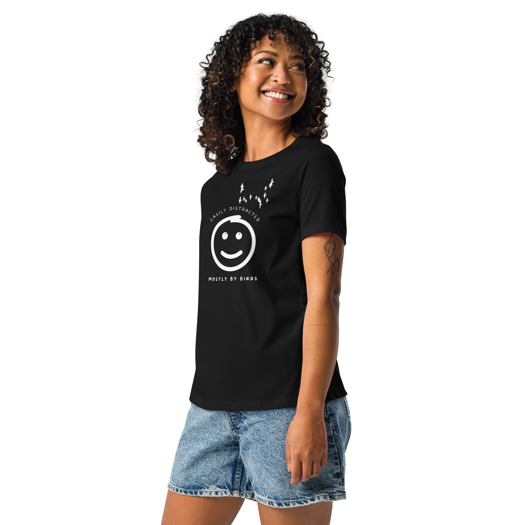 Black women's bird t-shirt with a smiley face looking up and to the side at a flock of birds surrounded by the words, "Easily Distracted" above and, "Mostly by Birds" below. Worn by a woman.