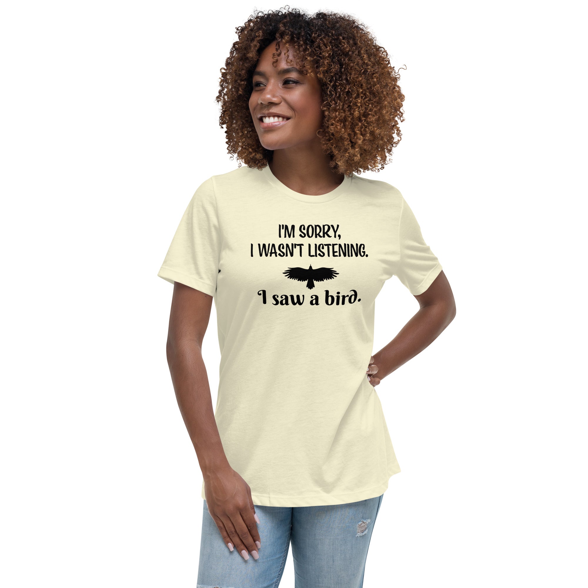 Light yellow women's bird t-shirt with the words I'm sorry I wasn't listening, I saw a bird. And a graphic of a bird flying. Worn by a woman.