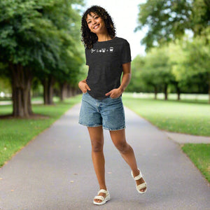 Dark heather gray women's bird t-shirt celebrating bird watching and coffee with a graphic of binoculars, a bird, and a travel cup of coffee. Worn by a woman.