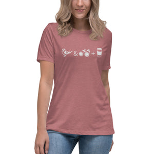 Mauve women's bird t-shirt celebrating bird watching and coffee with a graphic of binoculars, a bird, and a travel cup of coffee. Worn by a woman.