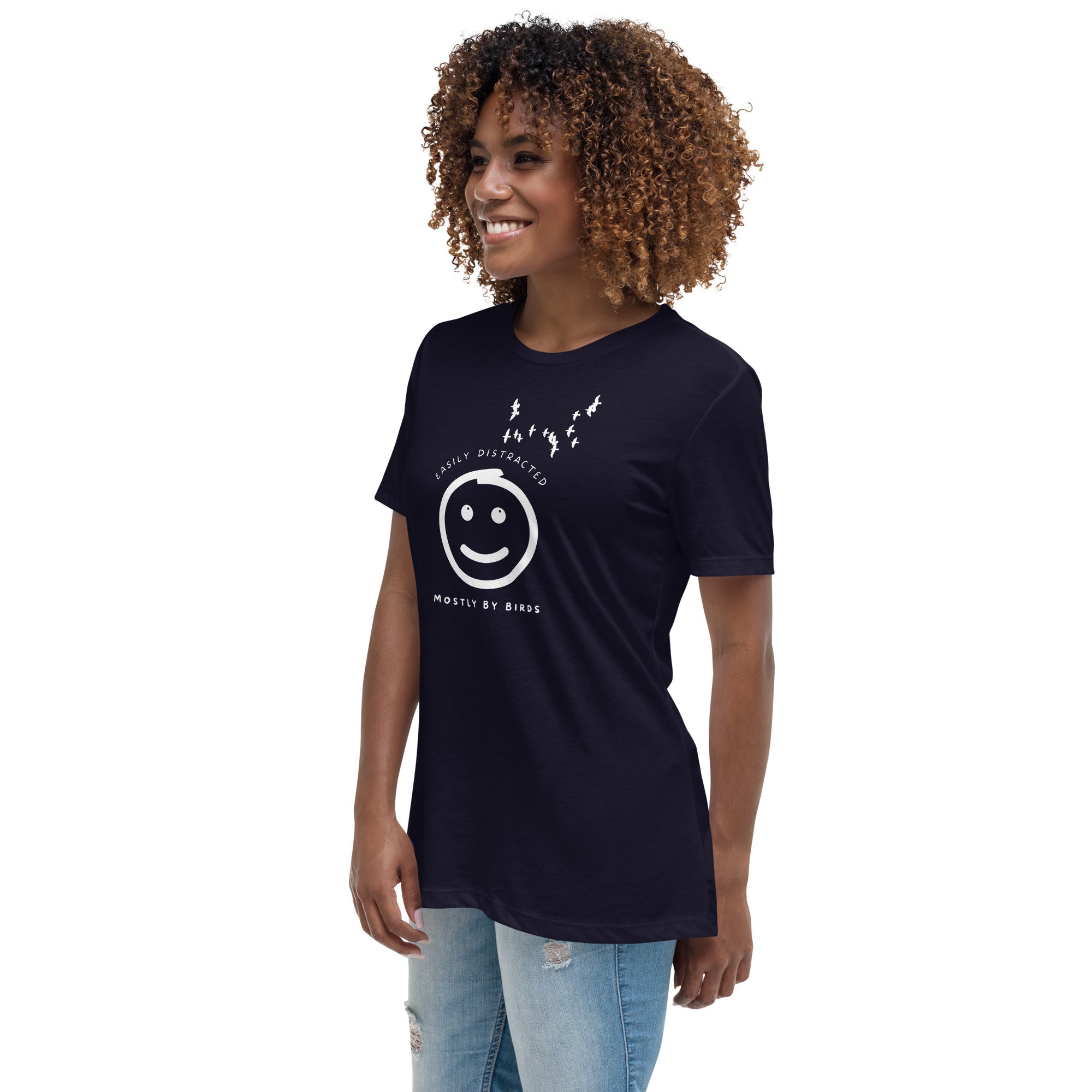 Navy blue women's bird t-shirt with a smiley face looking up and to the side at a flock of birds surrounded by the words, "Easily Distracted" above and, "Mostly by Birds" below. Worn by a woman.