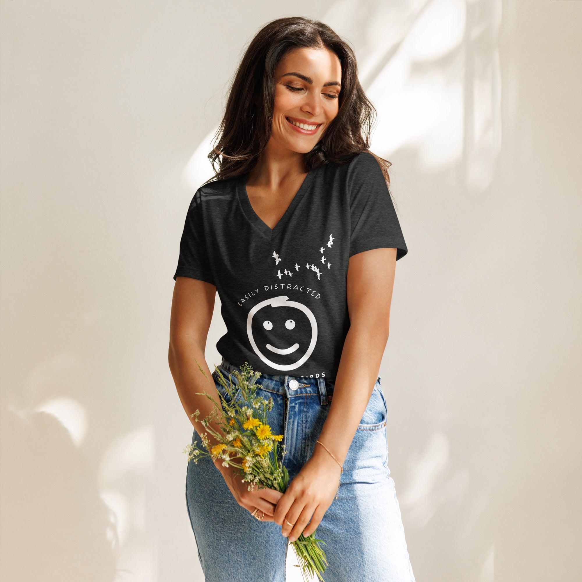 Dark heather grey women's v-neck bird t-shirt with a smiley face looking up and to the side at a flock of birds surrounded by the words, "Easily Distracted" above and, "Mostly by Birds" below.