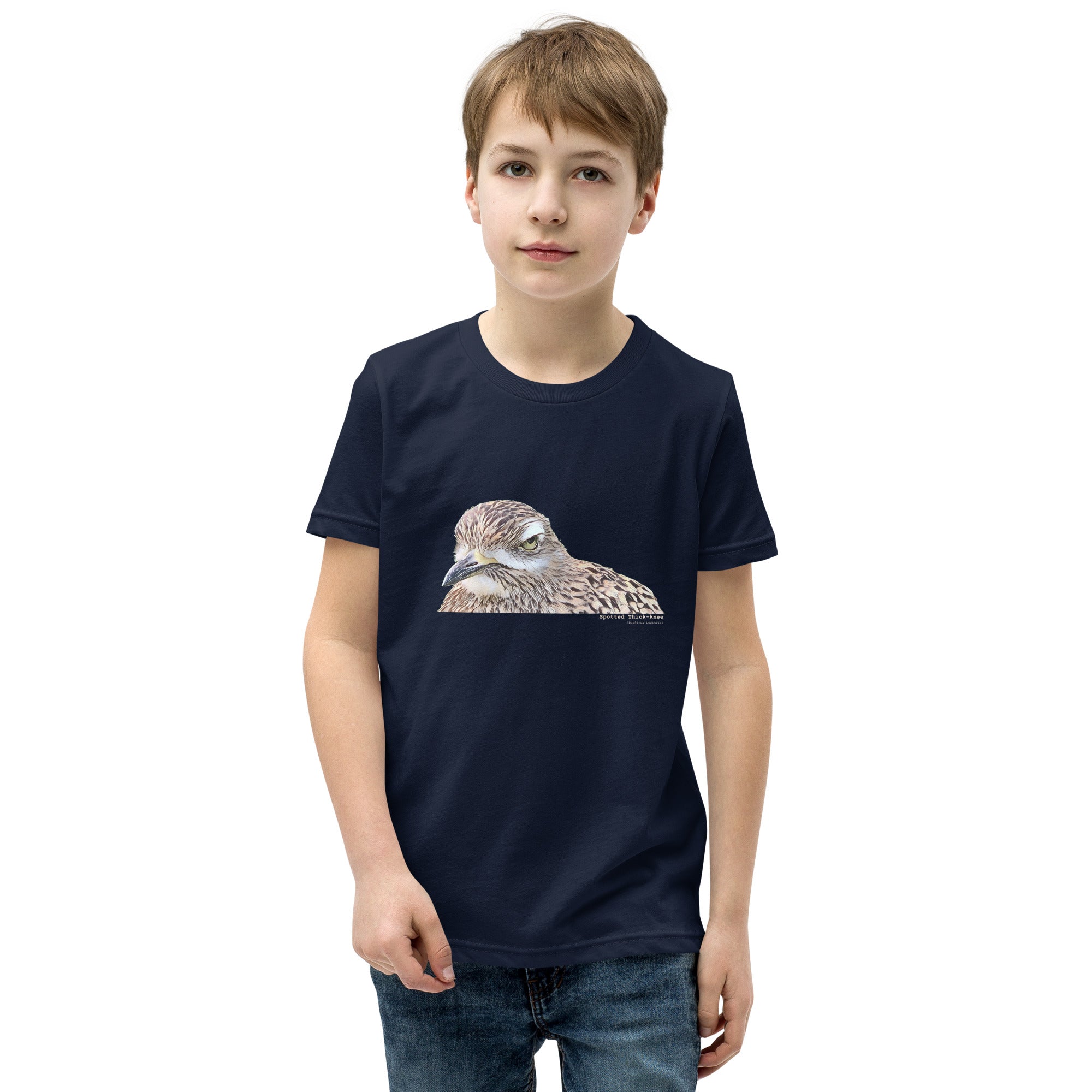 Navy unisex youth bird t-shirt with an illustrated picture of a spotted thick-knee bird looking grumpy. The words spotted thick-knee are written below the illustration, including the scientific name. Worn by a boy.