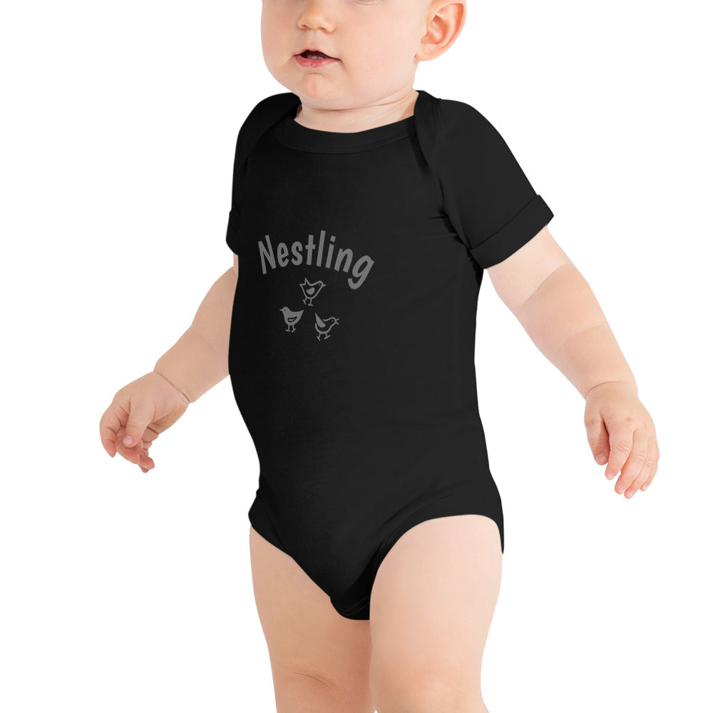 Pink one-piece baby suit with the word Nestling on the front above three small birds in dark grey.