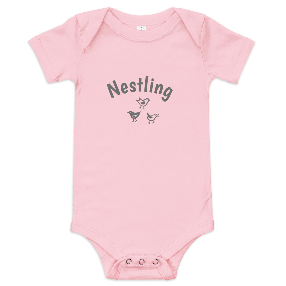 Pink one-piece baby suit with the word Nestling on the front above three small birds in dark grey.