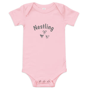 Pink one-piece baby suit with the word Nestling on the front above three small birds in dark grey.