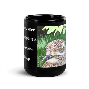 Black 15 ounce mug with graphic of a spotted thick-knee looking grumpy amongst a leafy background. In view are various common names for the Spotted Thick-knee and its scientific name.