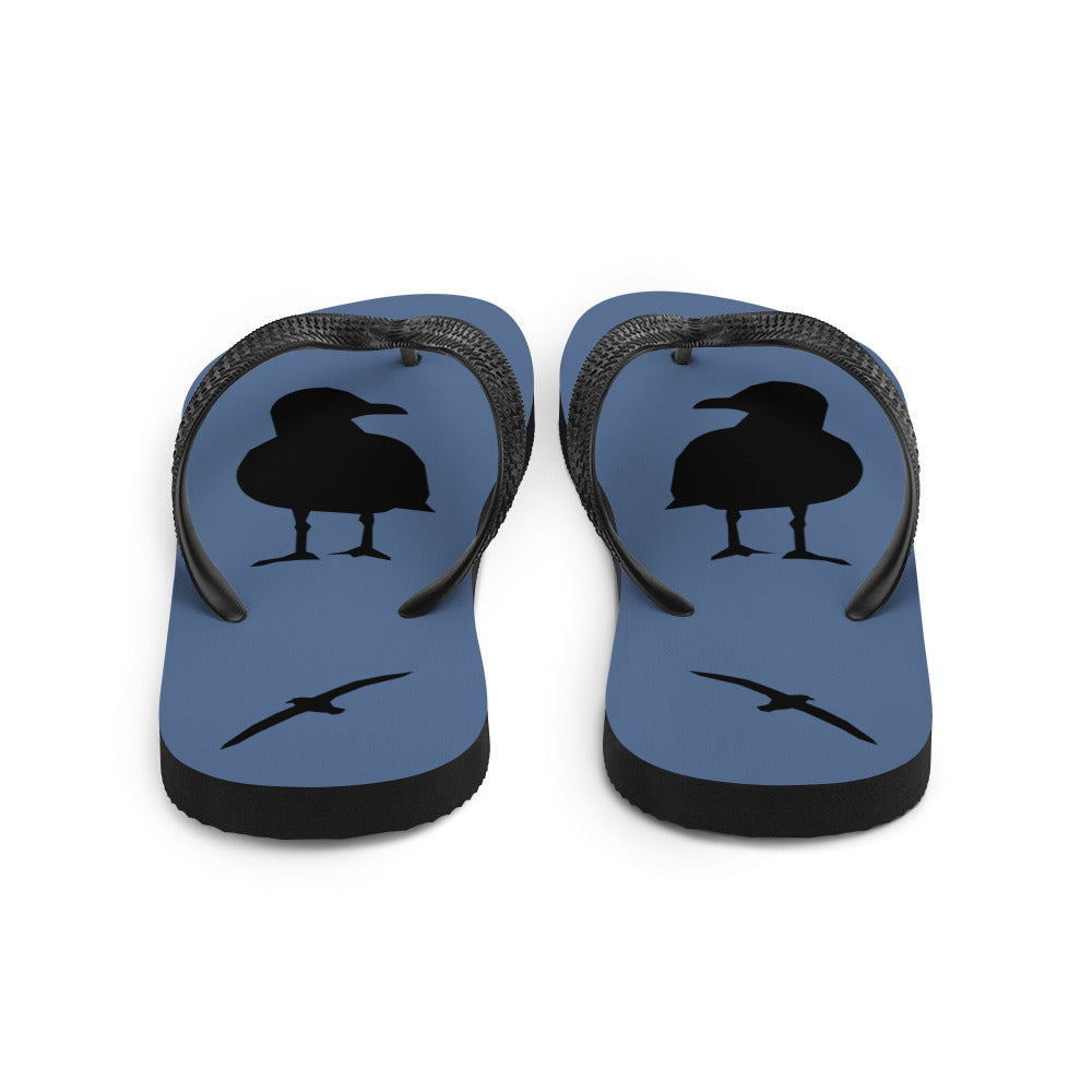 A pair of blue flip-flops with black strap and a silhouette of a seagull standing and smaller ones flying, viewed from the back.