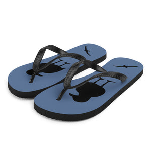 A pair of blue flip-flops with black strap and a silhouette of a seagull standing and smaller ones flying, viewed from the front right.