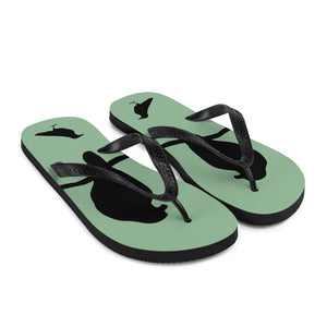 A pair of sea green flip-flops with black strap and a silhouette of a crow on a branch, viewed from the front at an angle.